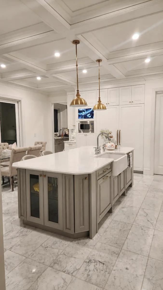Grey painted kitchen island with white perimeter cabinets and brass pendant lights by Johhan Painting
