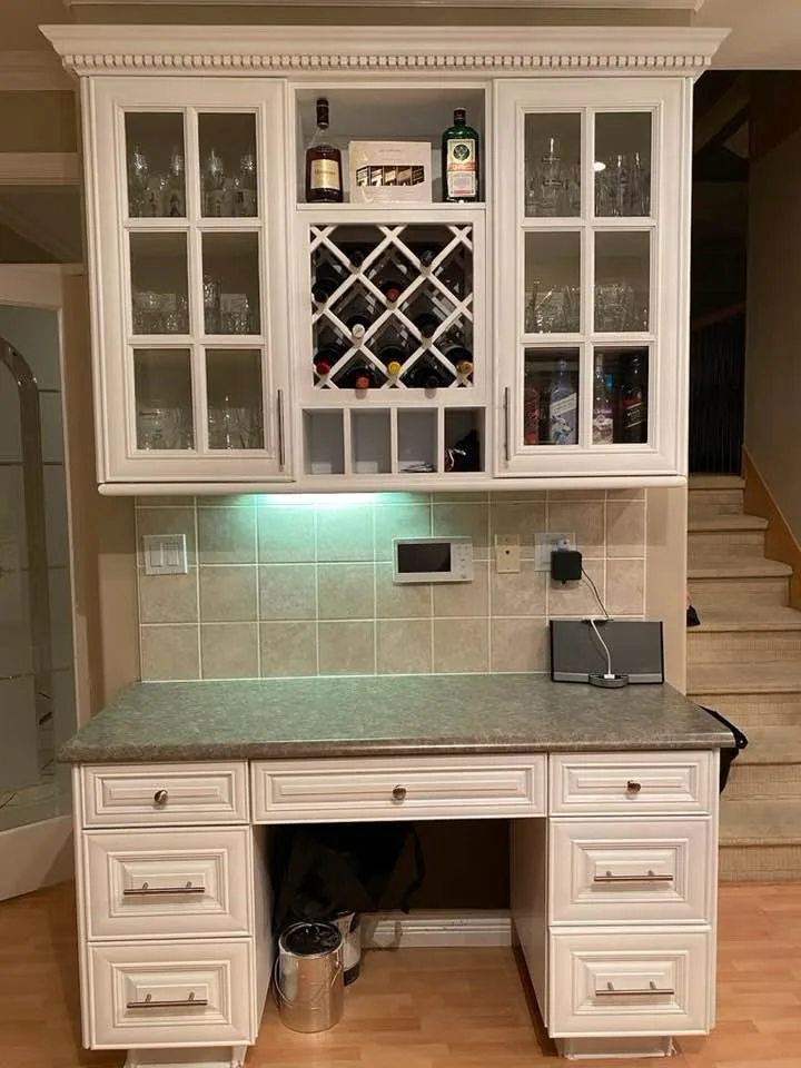 White painted kitchen bar cabinets with glass doors and a wine rack by Johhan Painting