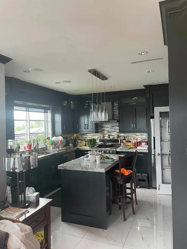 Dark charcoal painted kitchen cabinets with a marble island by Johhan Painting